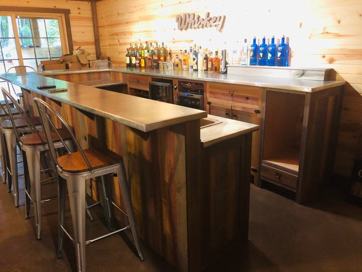 U-shaped home bar in reclaimed barn wood with a zinc countertop and stools