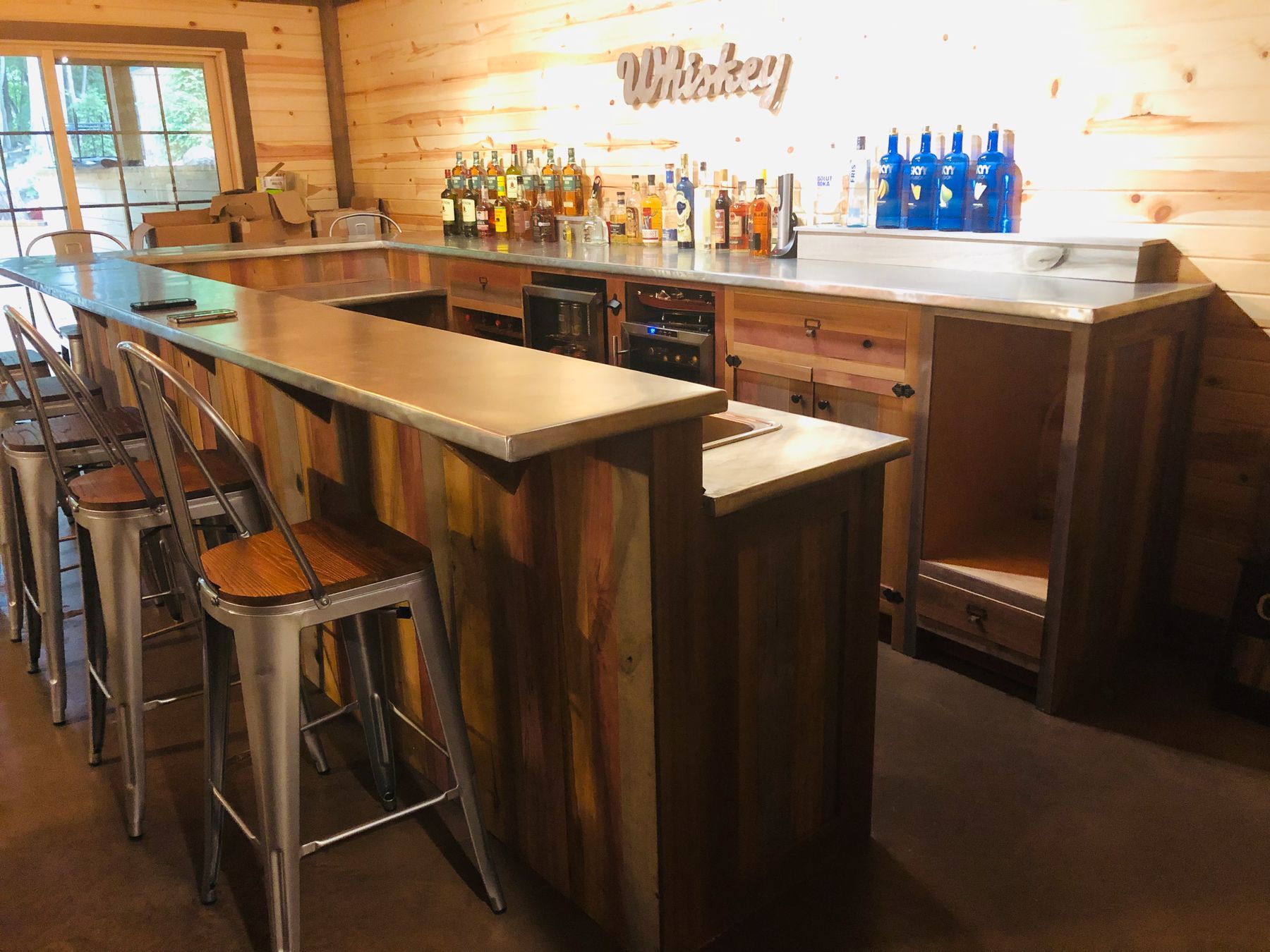 U-shaped home bar in reclaimed barn wood with a zinc countertop and stools