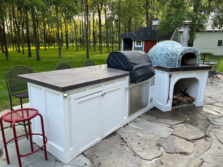 White cedar outdoor kitchen island with a grill and a mosaic-tiled pizza oven